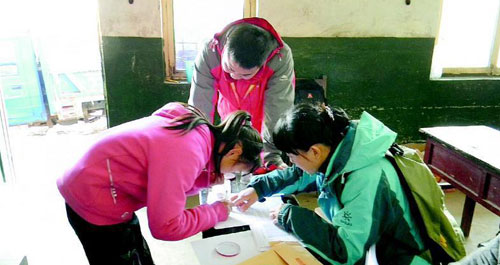 志愿者為困學生發(fā)放愛心助學金和御寒衣物