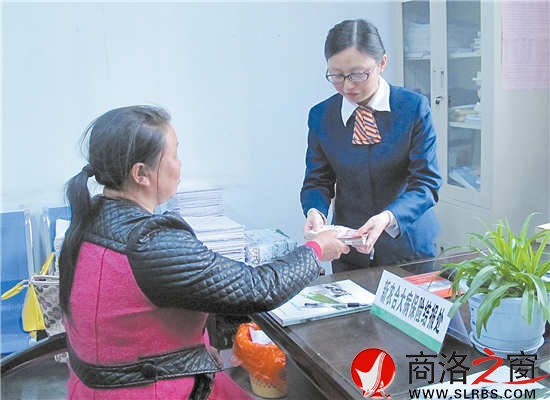 4月23日，謝自芳從工作人員手中接過大病保險報銷資金。